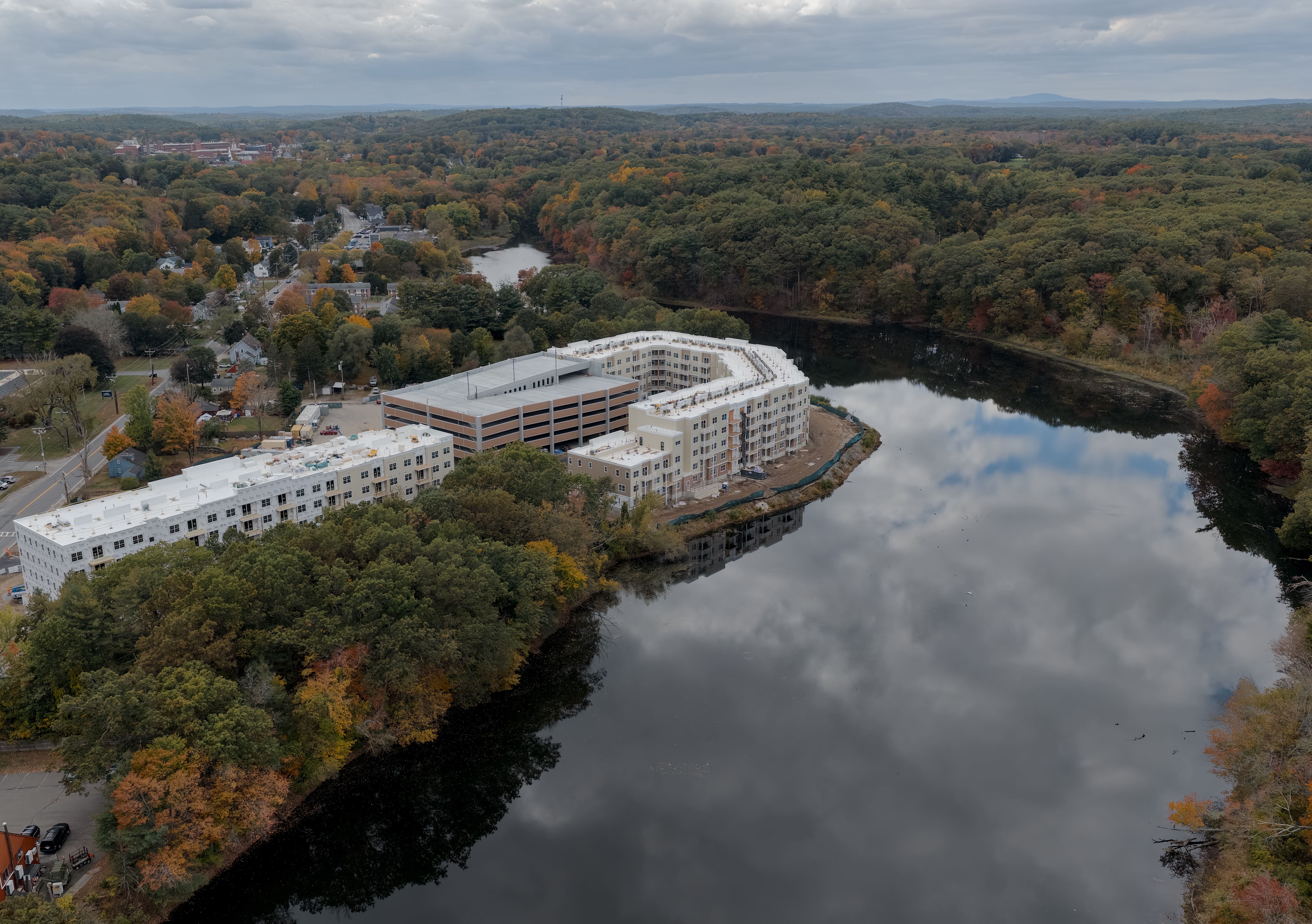 An apartment building complex that sits next to a river captured by a drone image during a commercial flight