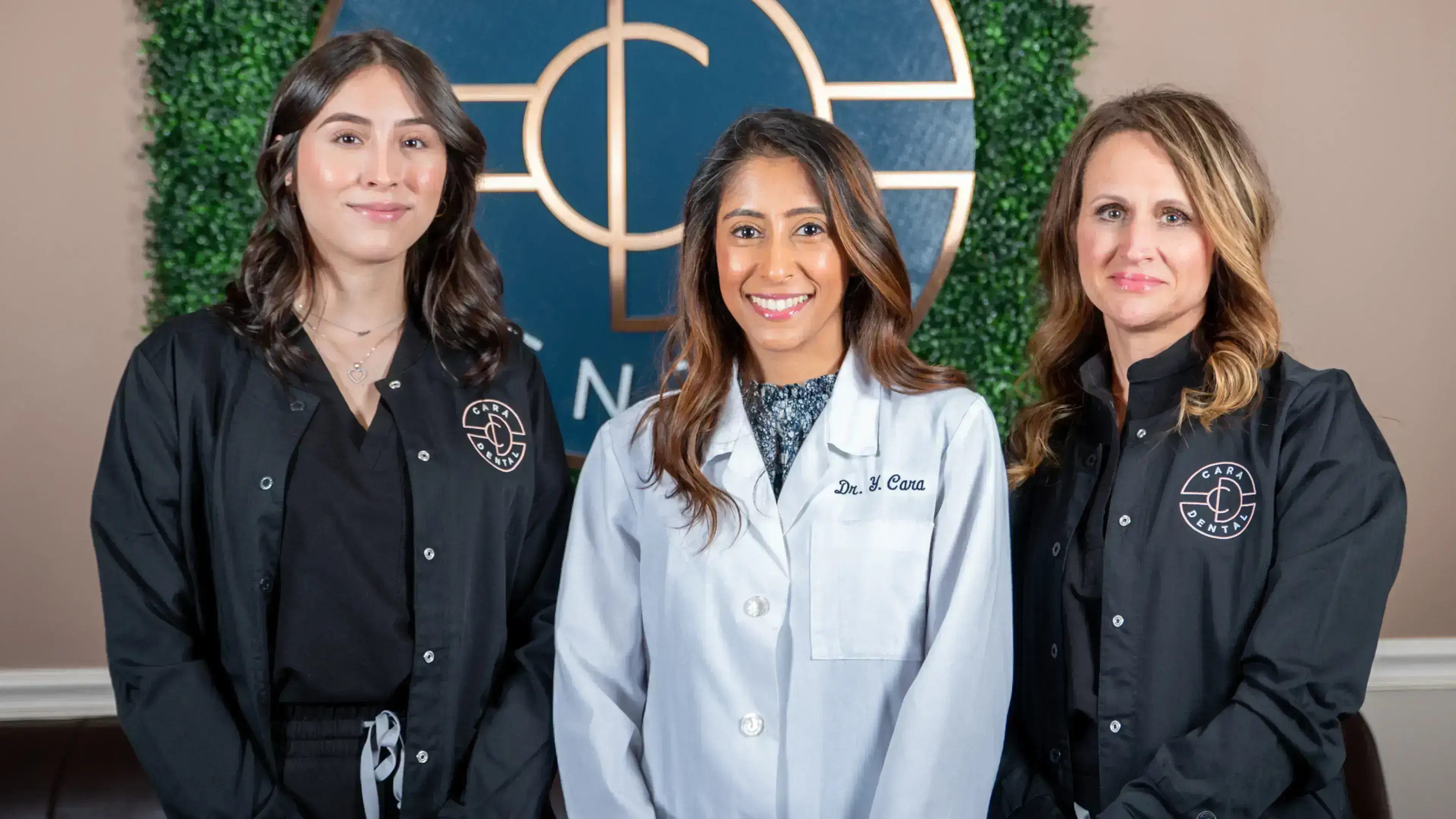 Dr. Cara and team smiling in front of logo