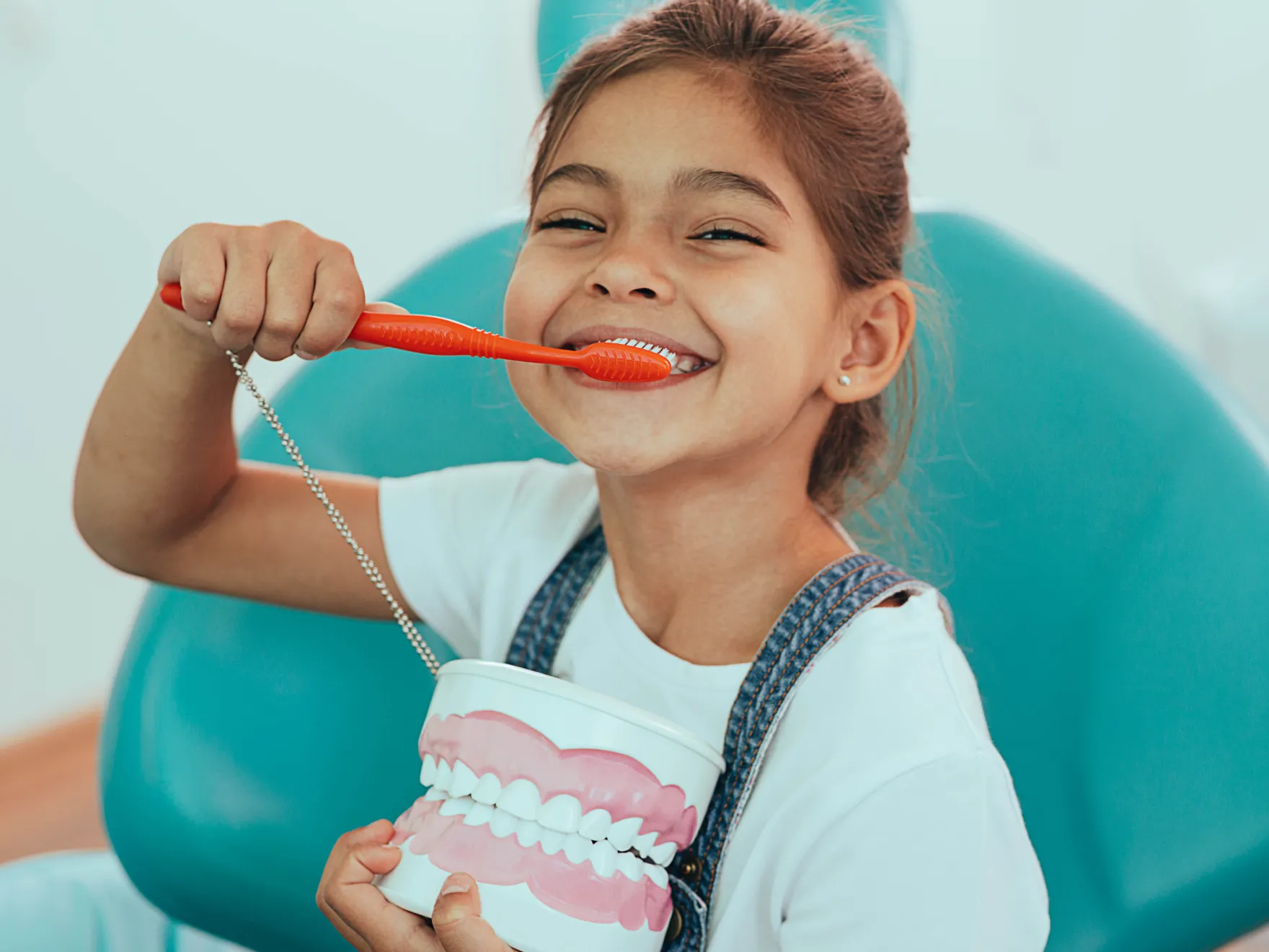 Child smiling in dental chair with toothbrush