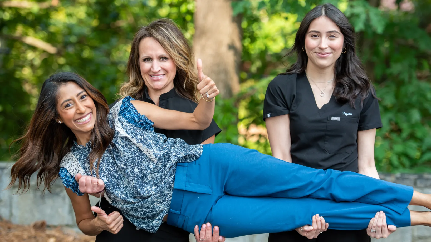 Two team members carrying Dr. Cara and smiling