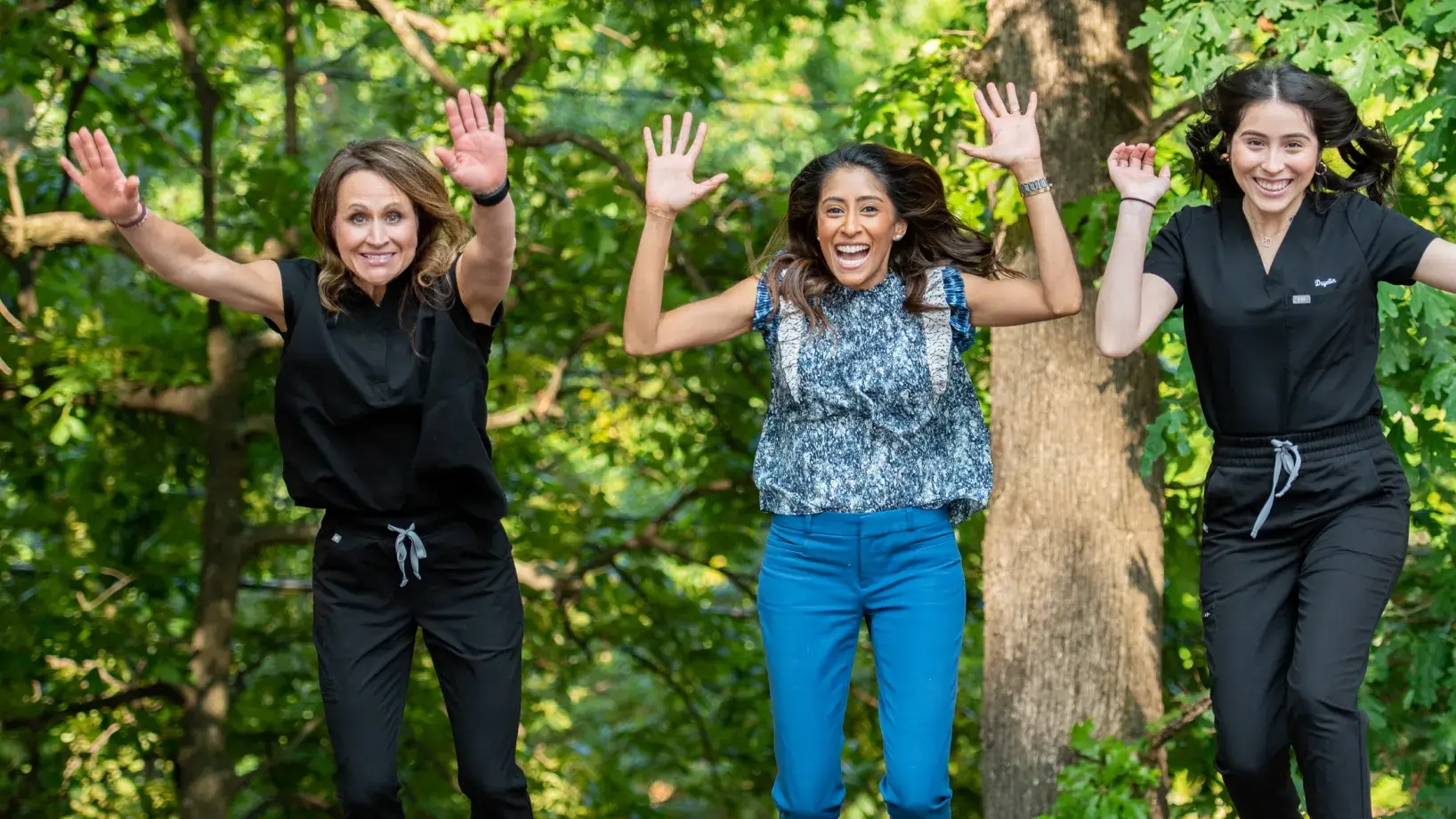 Dr. Cara and team jumping and smiling in green scenery