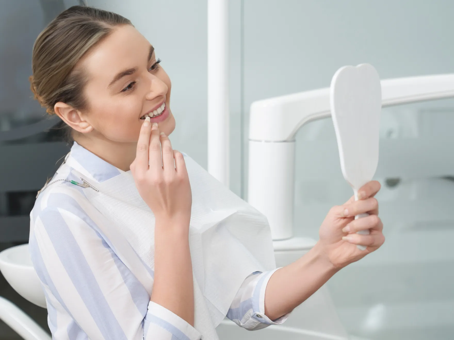 Patient smiling looking at her teeth in a mirror
