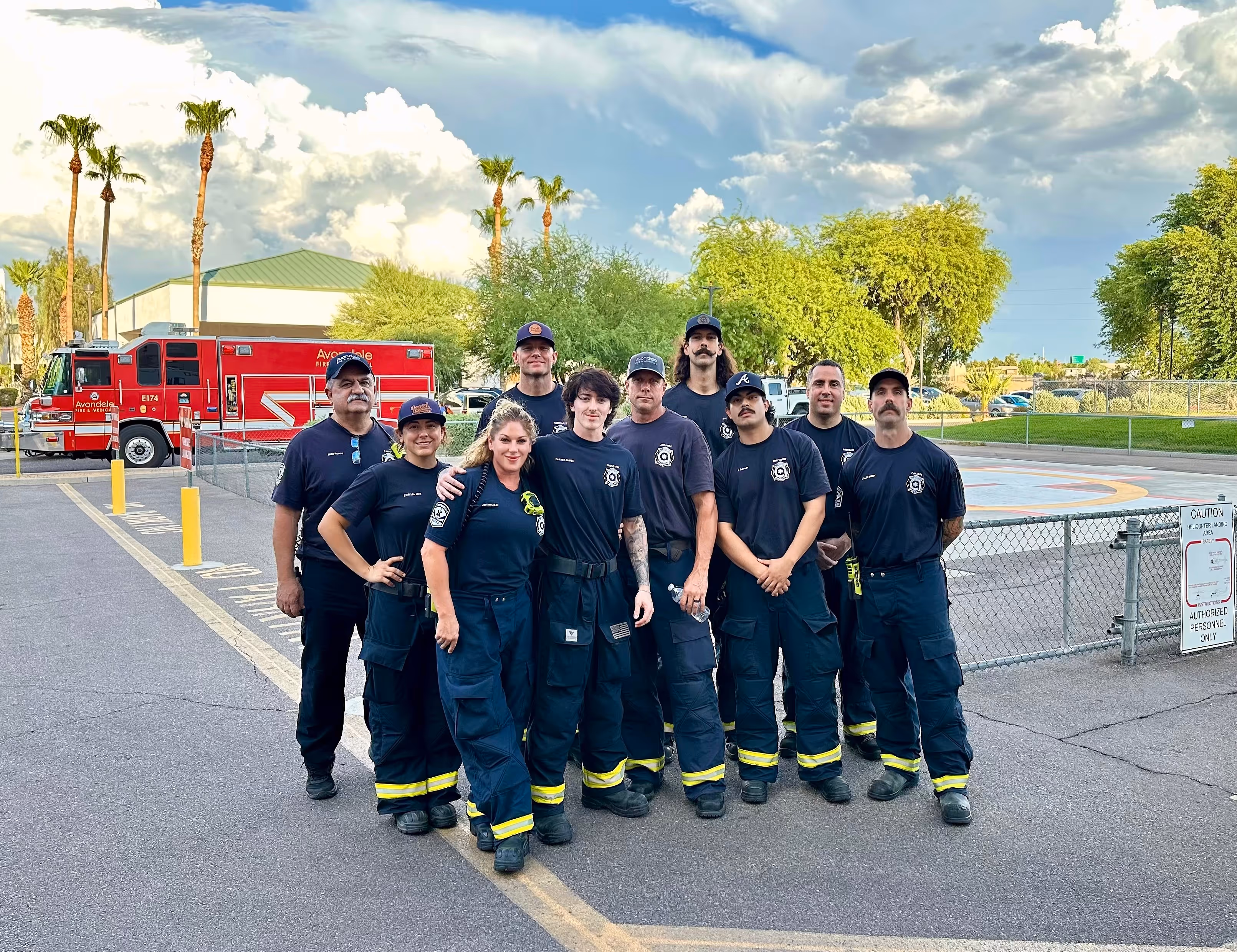 A group of men smiling and posing in front of a bright red fire truck.