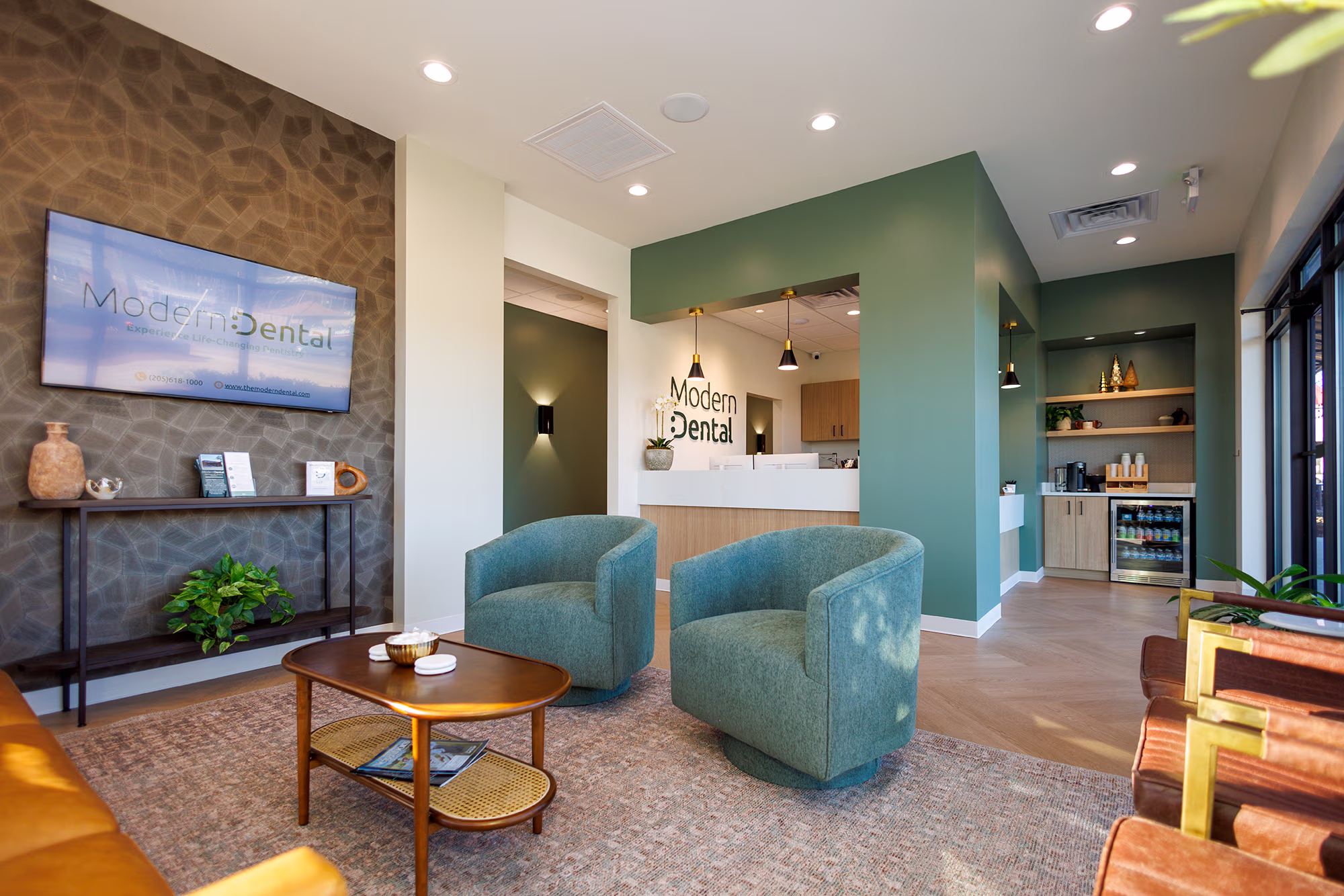 Modern Dental's waiting area with comfy green chairs and gold accents 