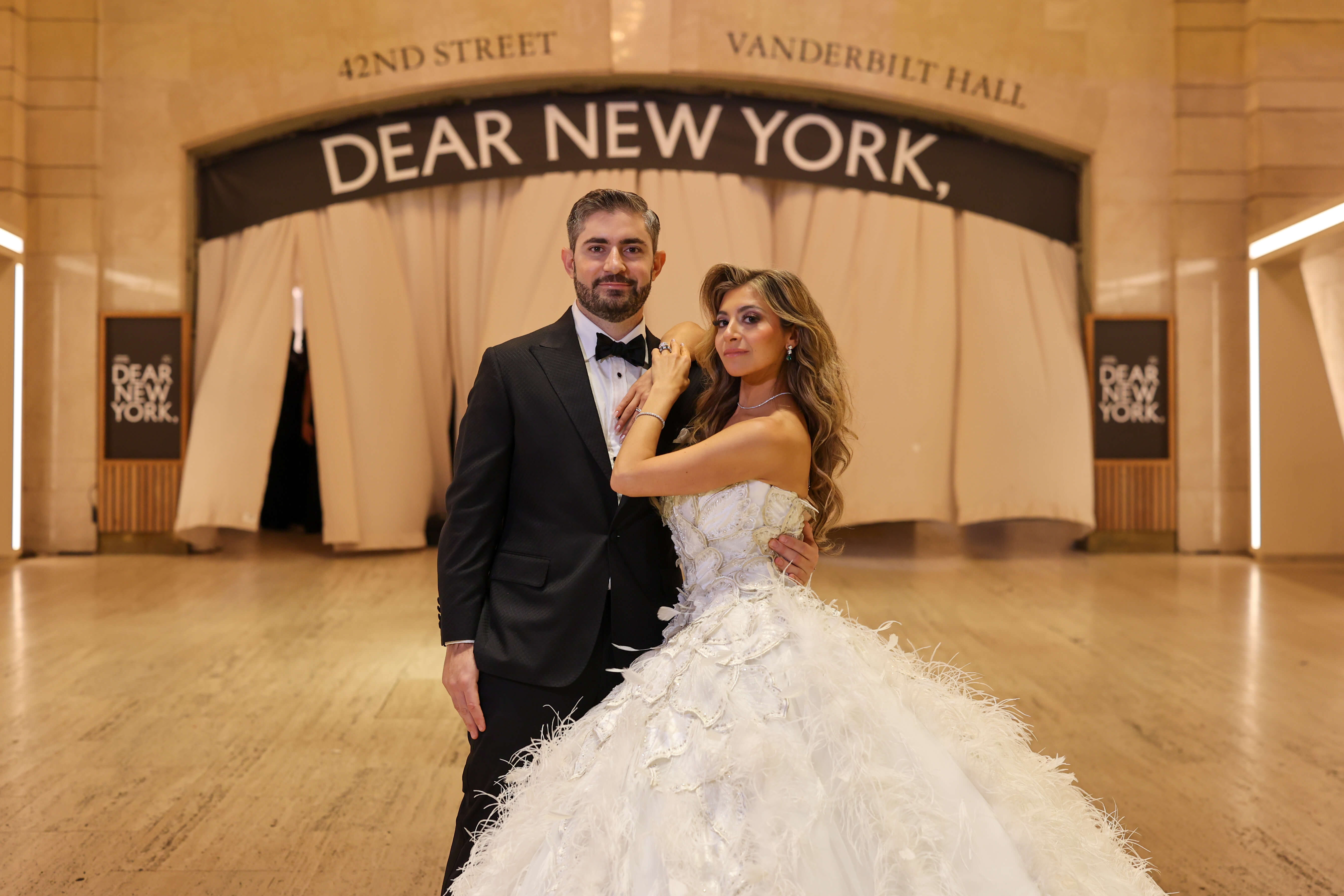 A husband and wife on their wedding day under the arch at Grand Central during the Dear New York, art installation. 