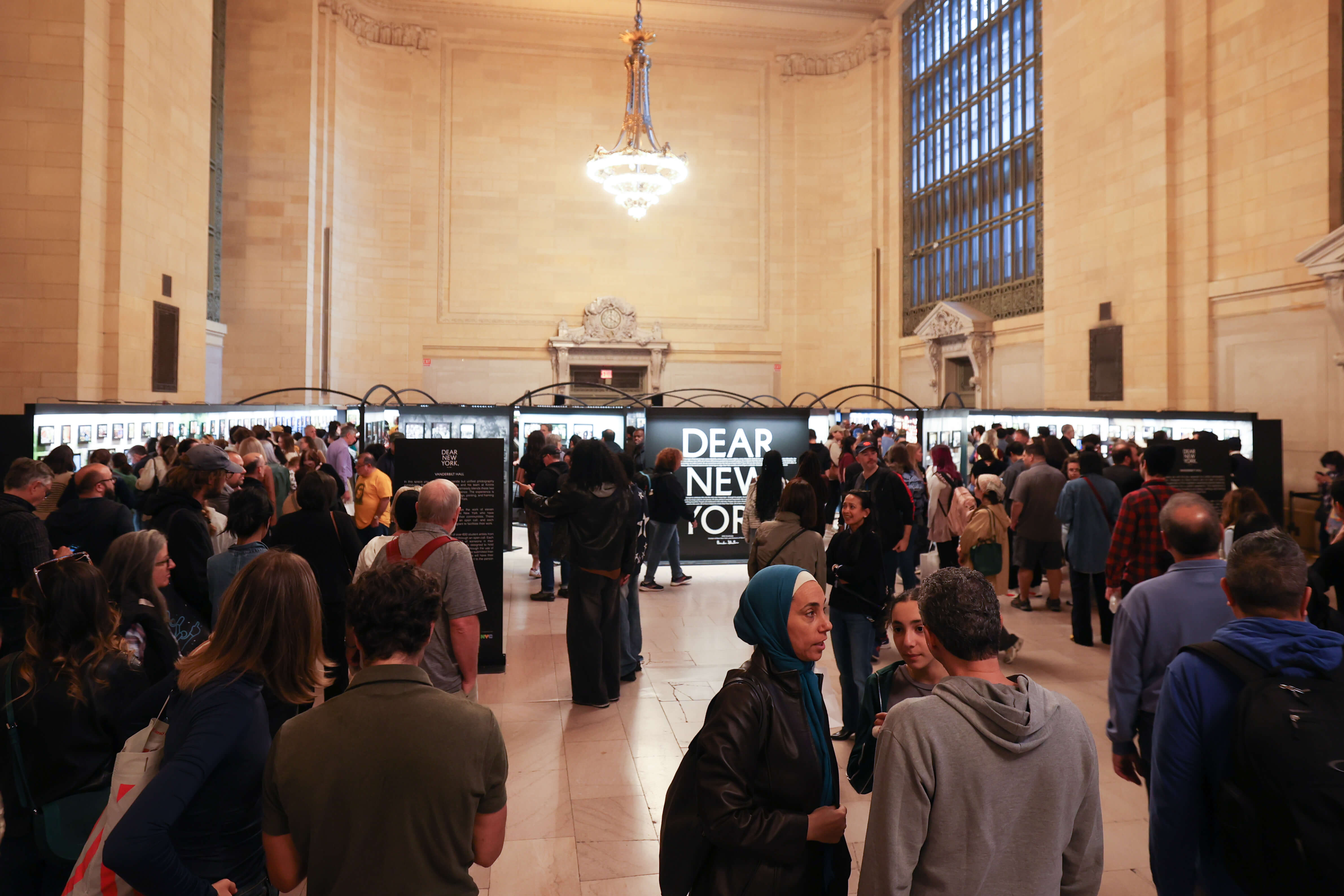People looking at the exhibit in Vanderbilt Hall, Grand Central during Dear New York, an art installation. 