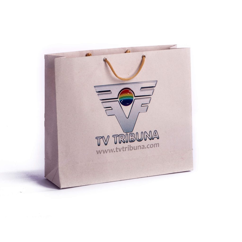 Beige paper shopping bag with gold rope handles, displaying a colorful TV Tribuna logo and website URL.