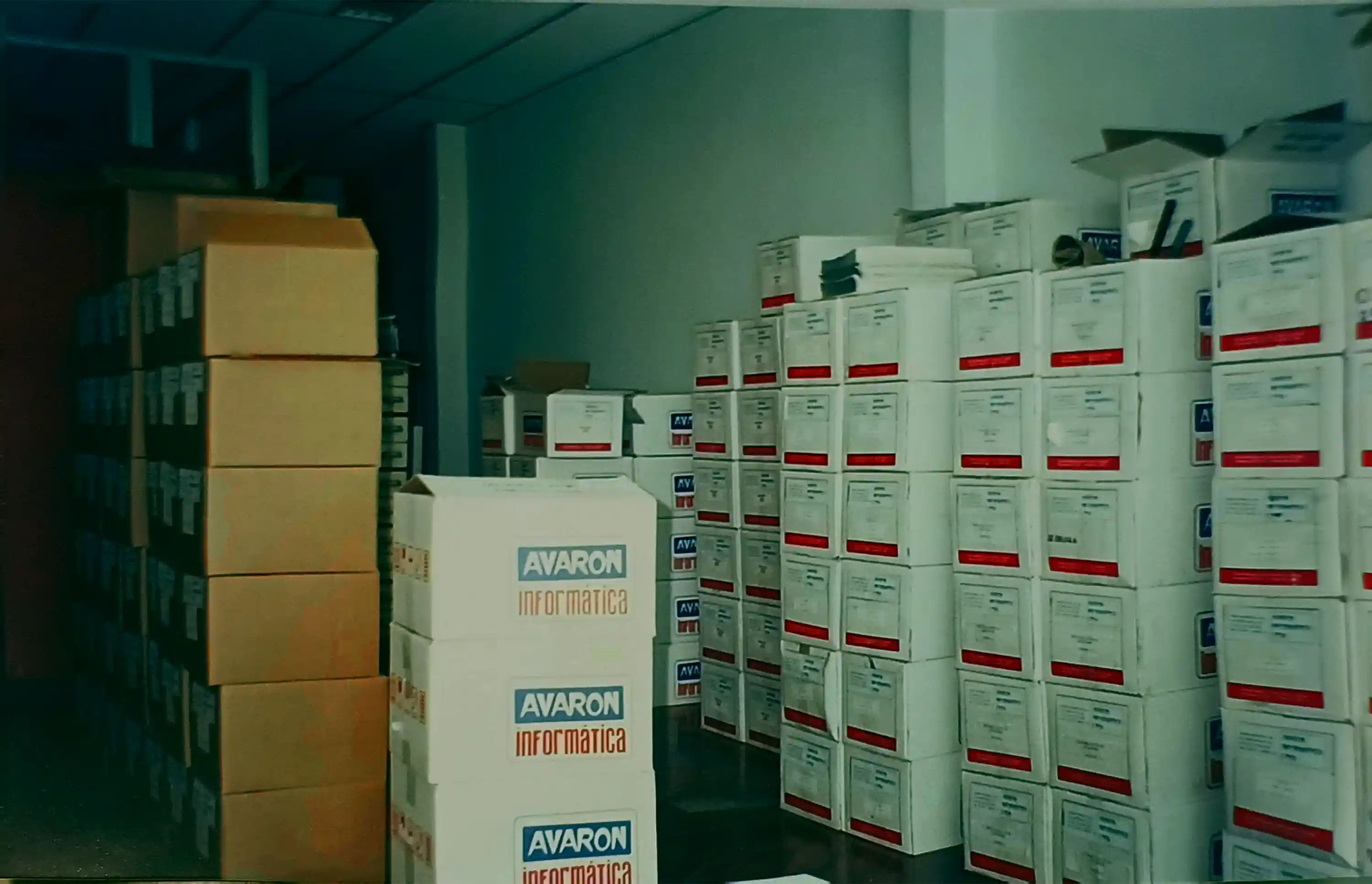 Storage room filled with stacks of cardboard boxes, some labeled 'Avaron Informatica'.