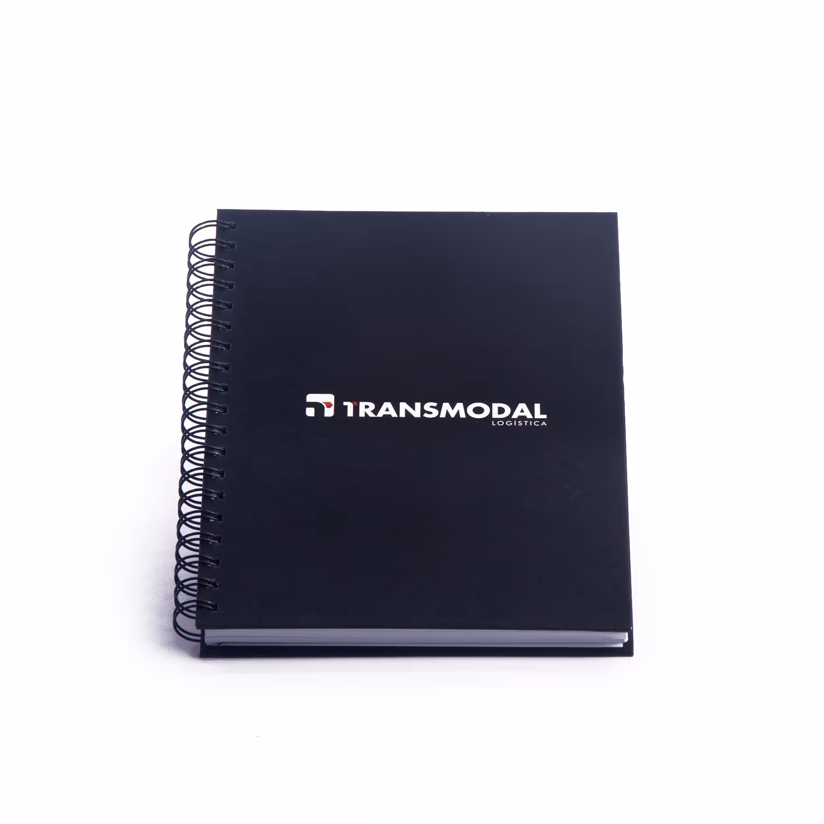 Closed black spiral-bound notebook with Transmodal Logística logo on the cover.