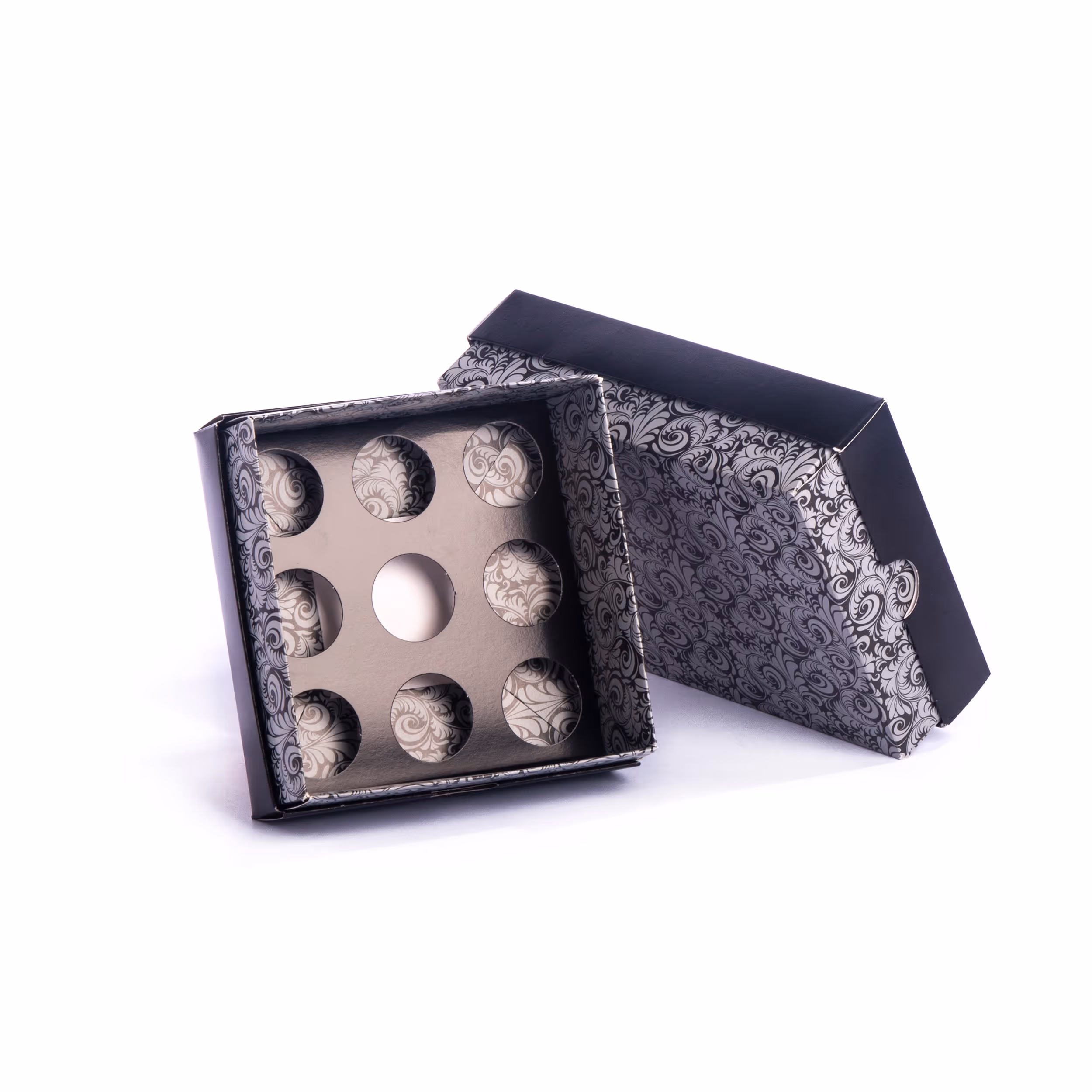 Open decorative black and silver box with cut-out circular compartments inside.