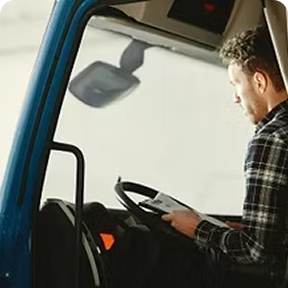 Truck driver sitting in the cab and reviewing documents before driving.