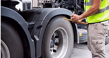 Inspector checking the tires of a commercial truck during a Level 1 roadside inspection.