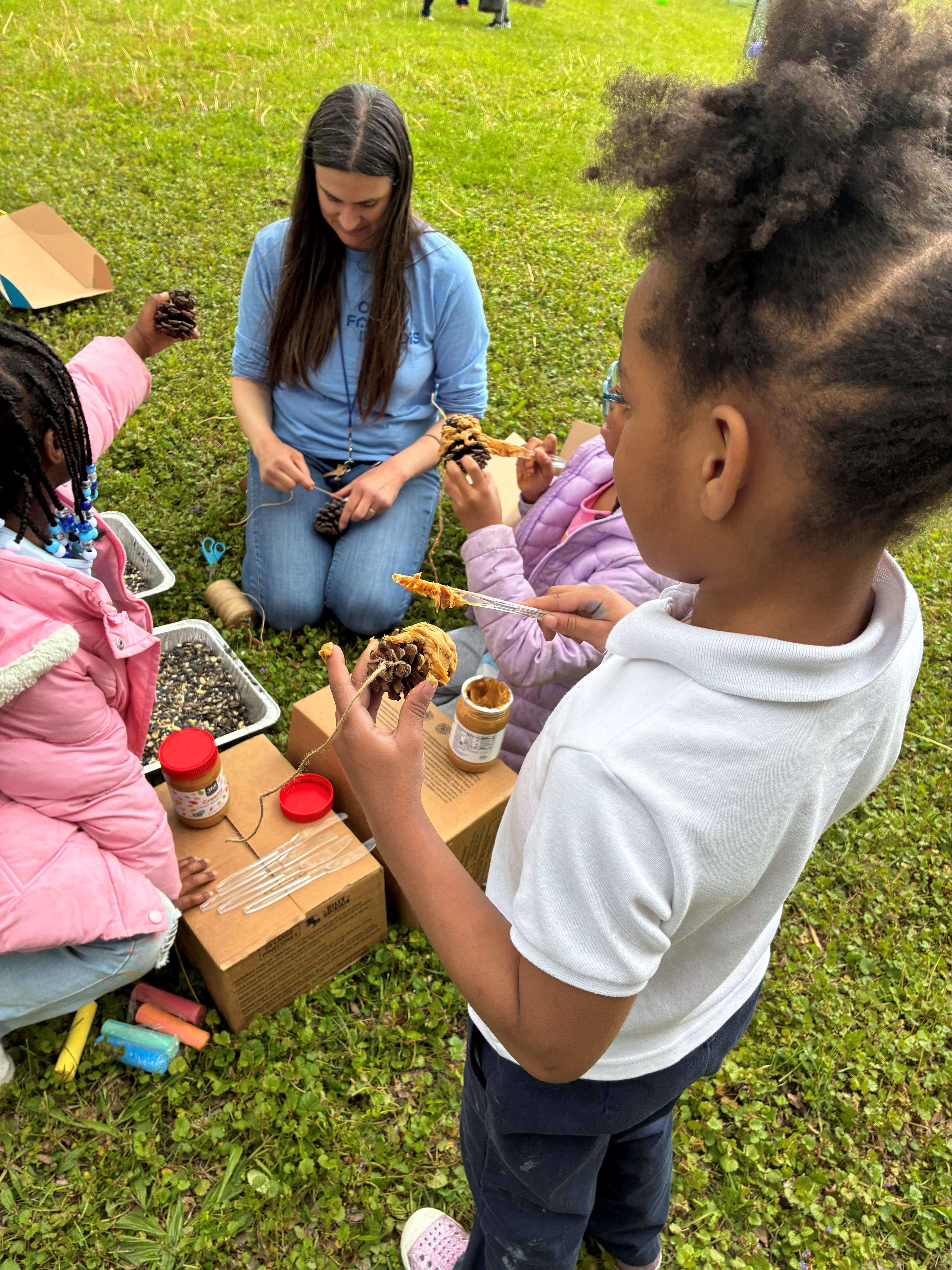 Emily makes pinecone bird feeders with the kids