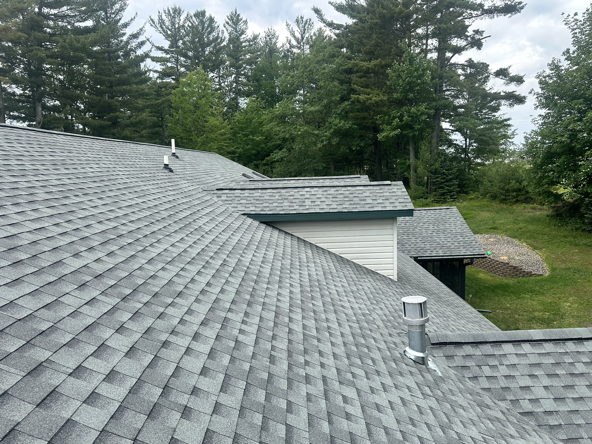 Close-up of gray architectural shingles and roof vents on duplex, showing clean lines and careful install