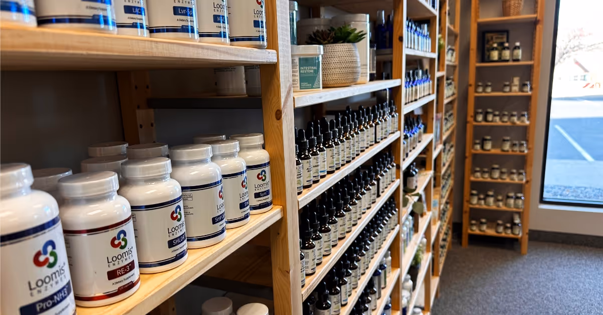 Wooden shelves stocked with various supplement bottles and dropper bottles in a well-lit store interior.
