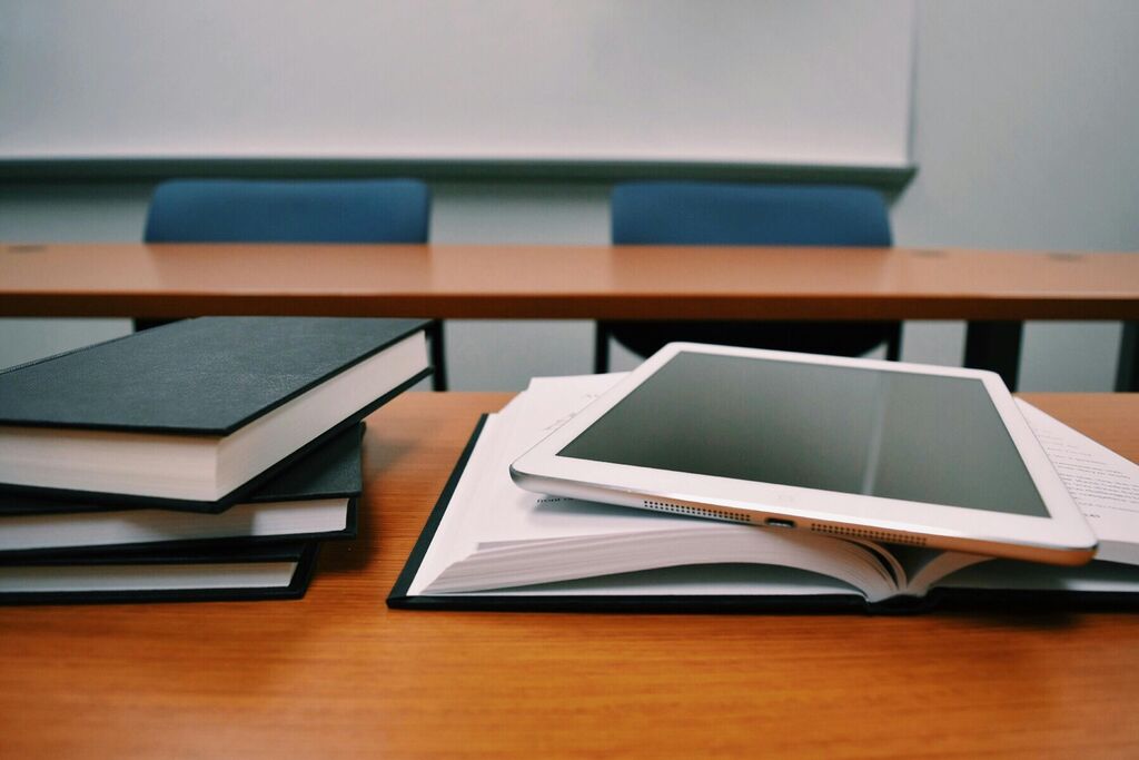 Books and notebooks on top of a desk in a classroom