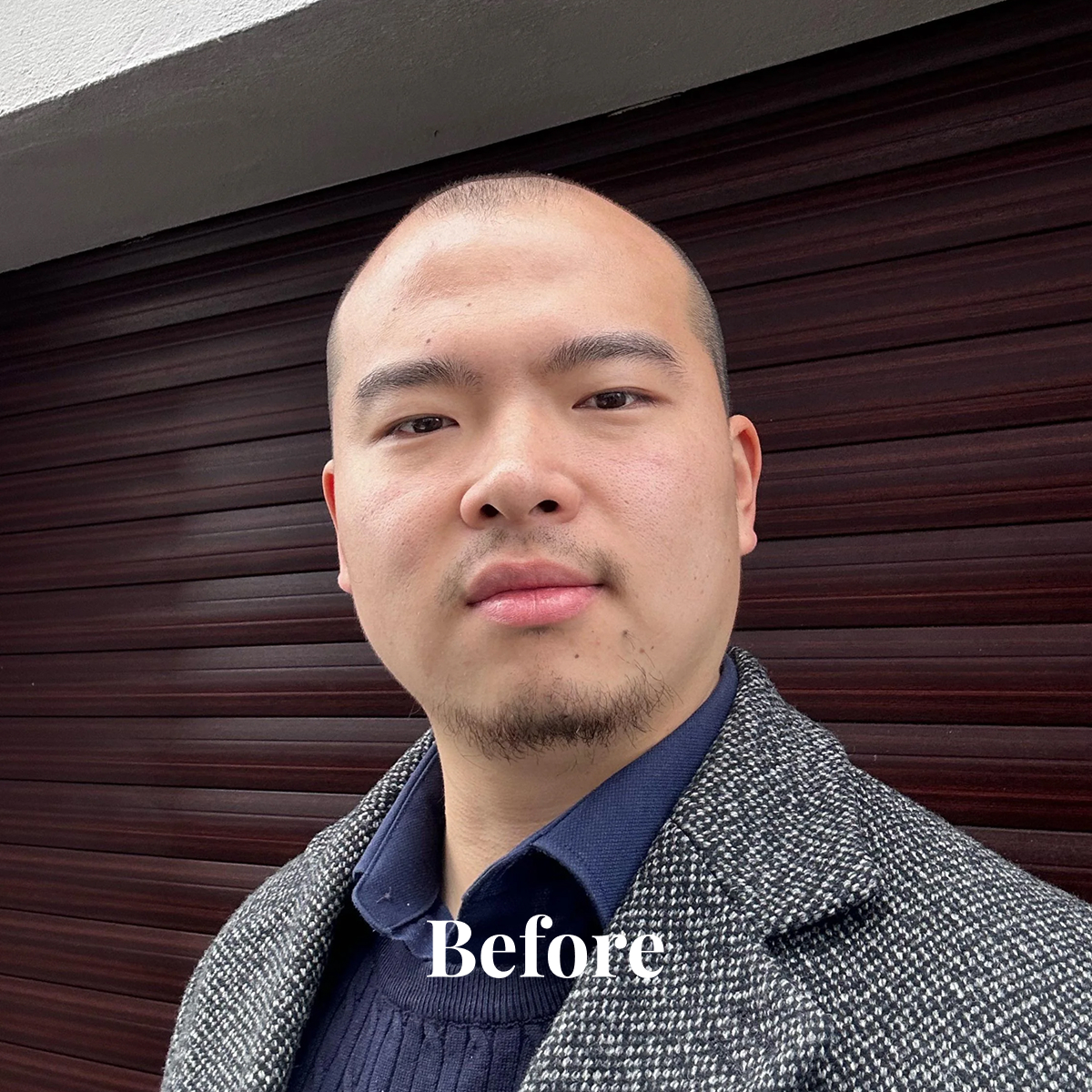 Portrait of a man with a shaved head and trimmed beard wearing a gray patterned coat and dark blue shirt, standing in front of a dark wooden garage door with the word 'Before' at the bottom.