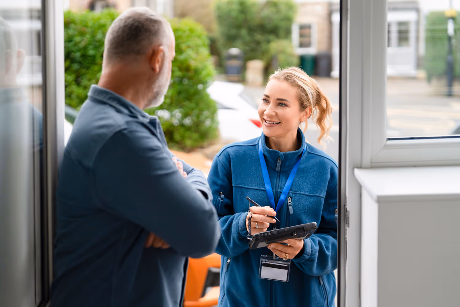 Smiling residential field sales representative speaking to a potential customer at their front door.