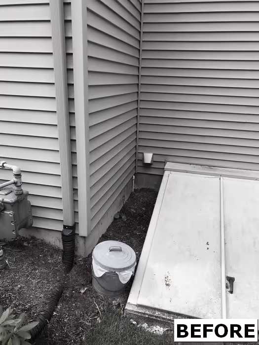 Side of the house with a utility cover and scattered debris.