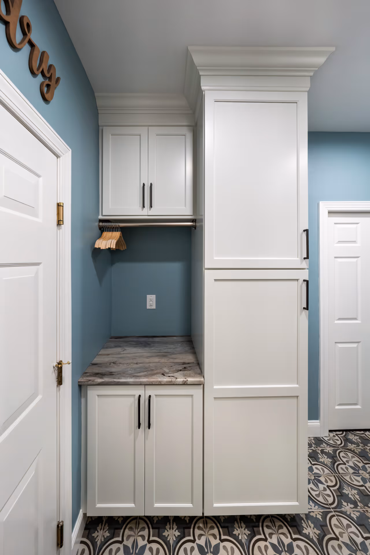 After: Spacious laundry room with tall cabinets and organized shelving.