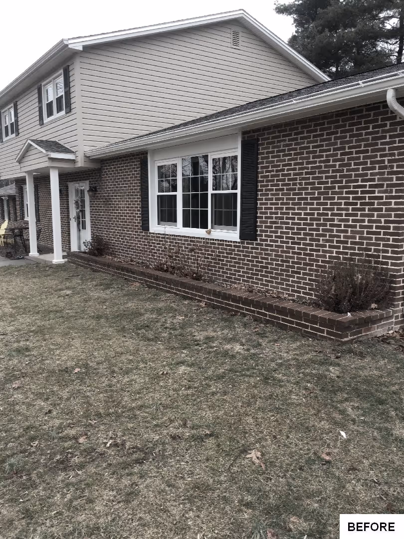 Before: Exterior view of the house with a grassy yard and cloudy sky.