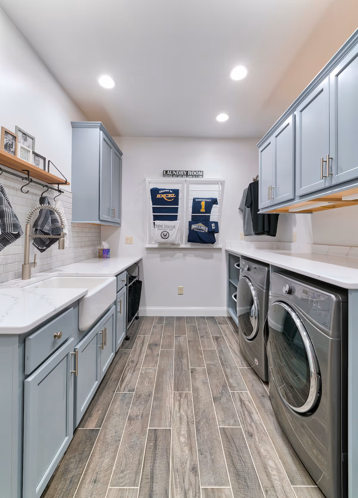Modern laundry room in mechanicsburg, pa featuring gray cabinets, a farmhouse sink, and stainless steel washers.