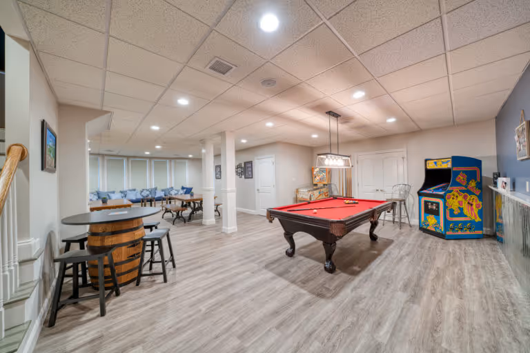 Contemporary basement featuring a red pool table, arcade game, and stylish seating area in Mechanicsburg, PA.