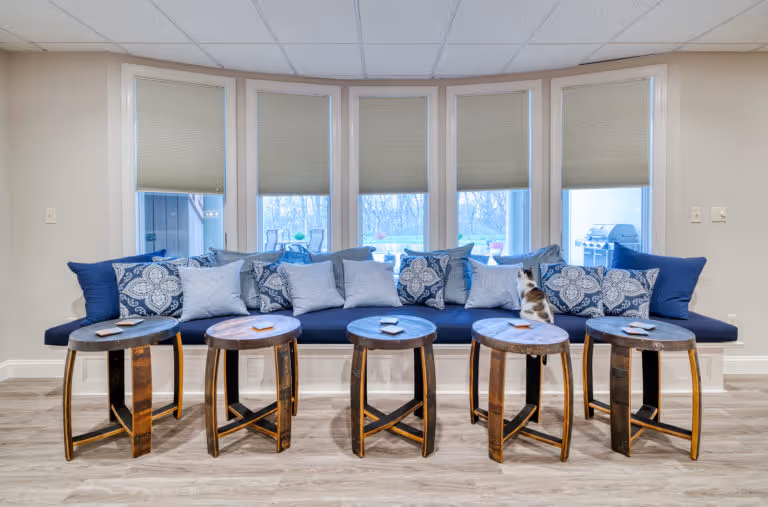 Spacious basement sitting area with comfortable blue bench seating and circular tables in Mechanicsburg, PA.