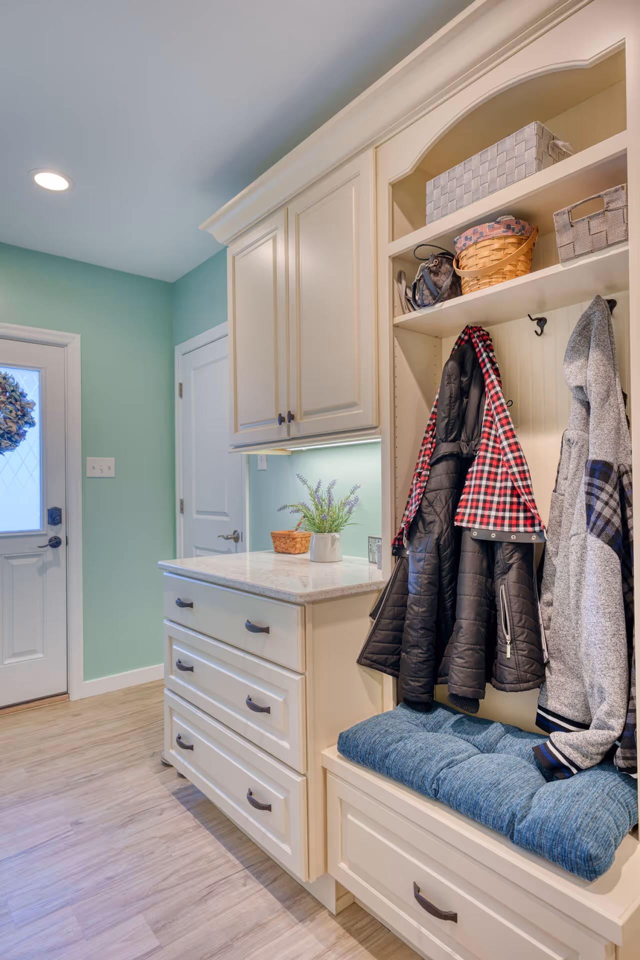 Elegant transitional mudroom in Lemoyne, PA featuring white cabinetry, a granite countertop, and a cozy seating area with blue cushion.