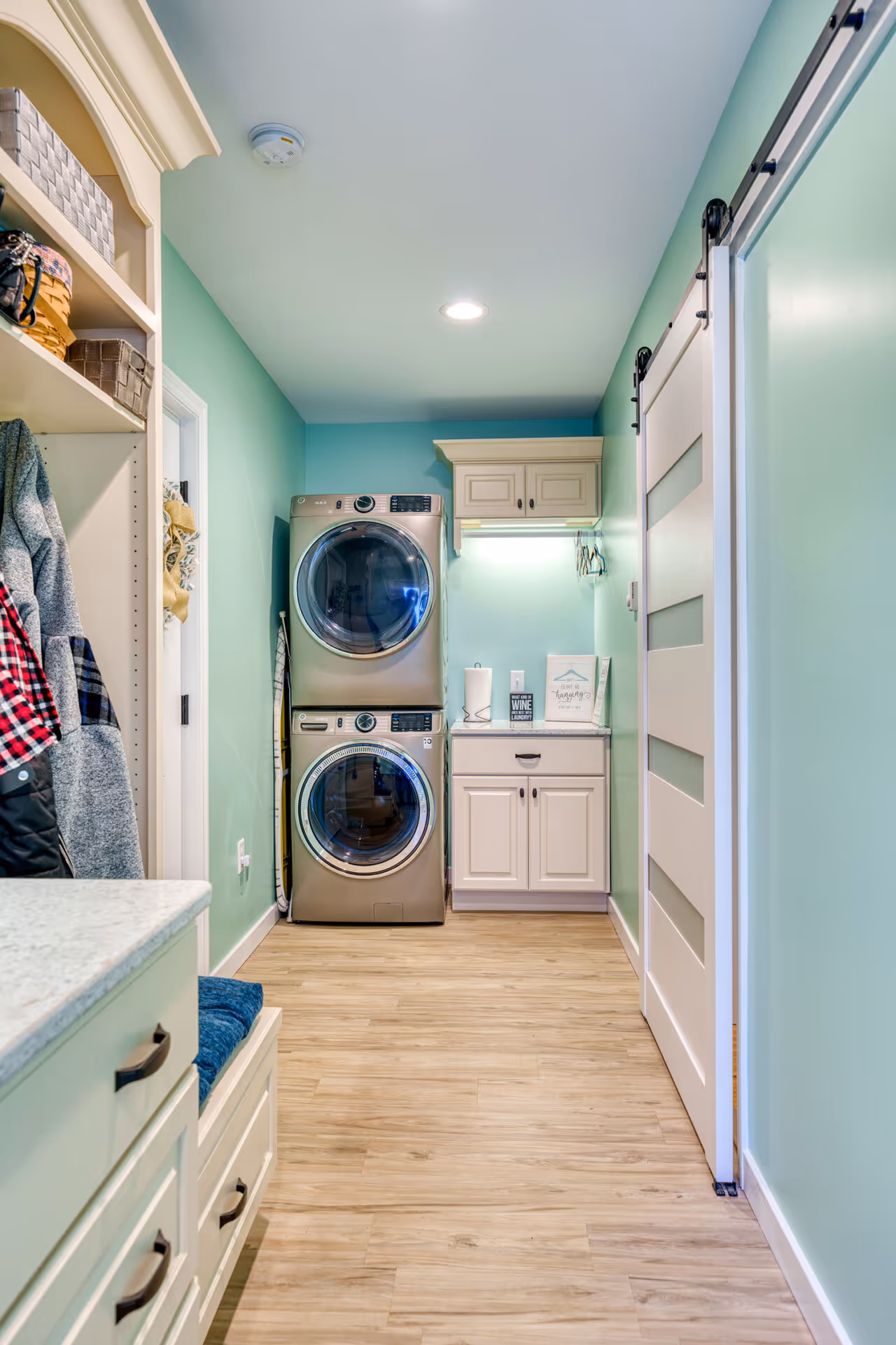 Contemporary laundry room with stacked washer and dryer, mint green walls, and light wood flooring in lemoyne, pa