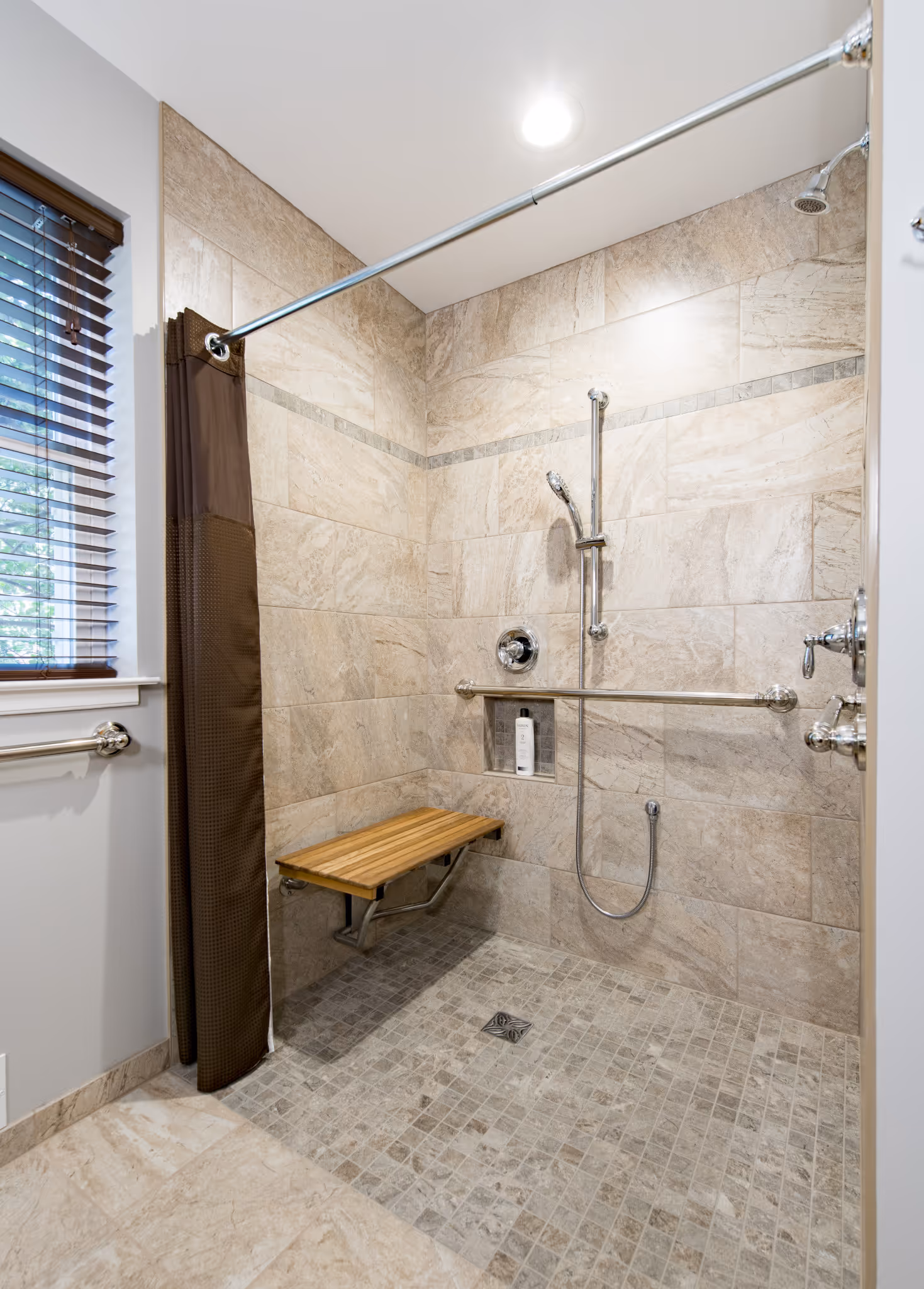 Accessible bathroom shower in New Cumberland, PA featuring a wooden bench and modern fixtures.