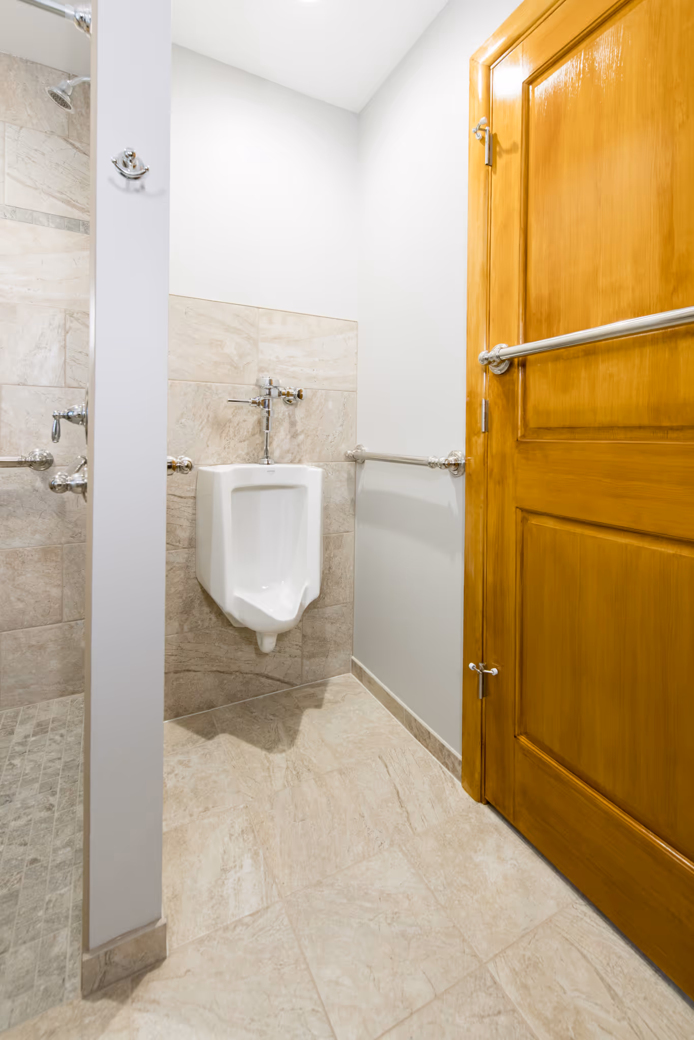 Modern bathroom in New Cumberland, PA featuring a wall-mounted urinal and stylish beige tile flooring.