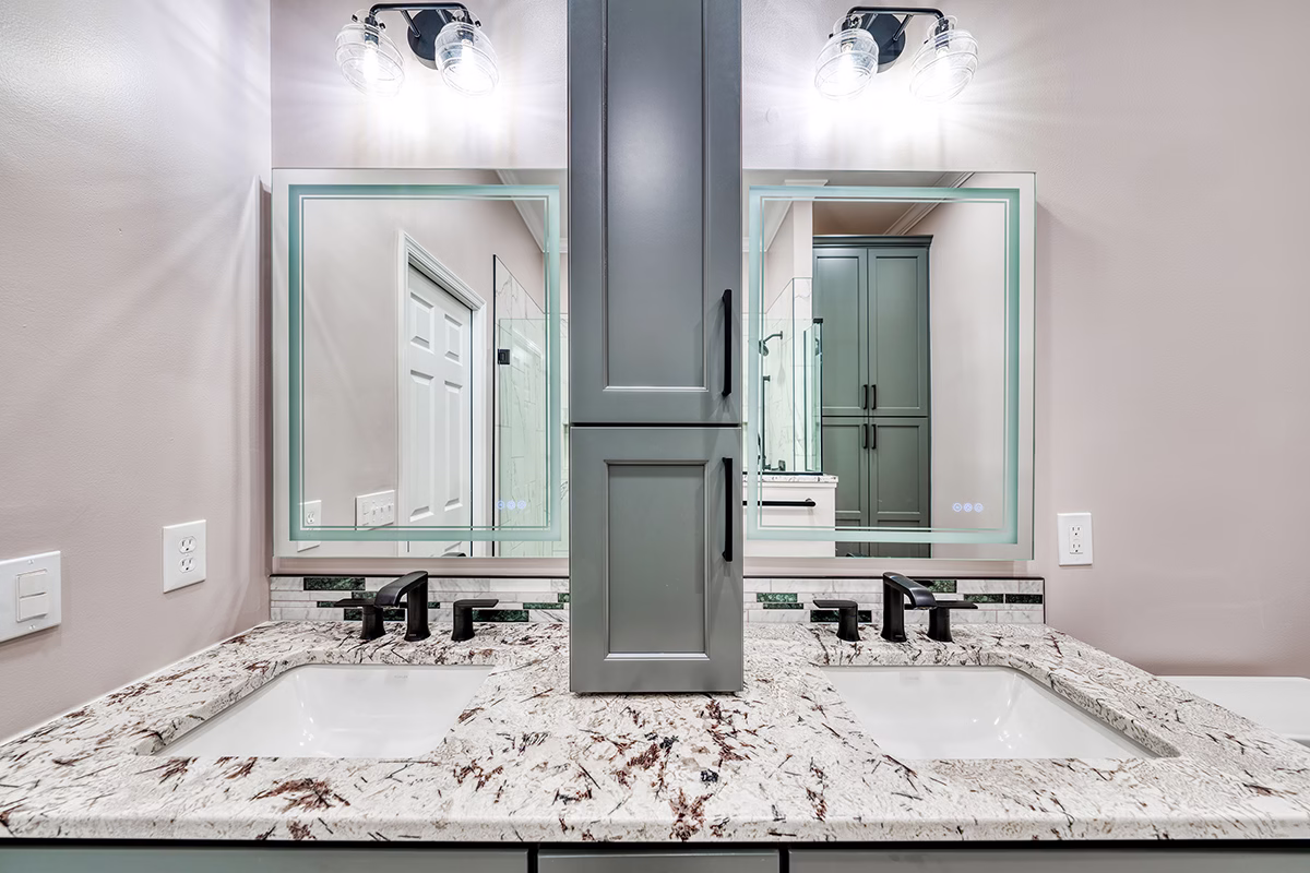 Modern primary bathroom in Harrisburg, PA featuring dual sinks, dark fixtures, and a stylish granite countertop.