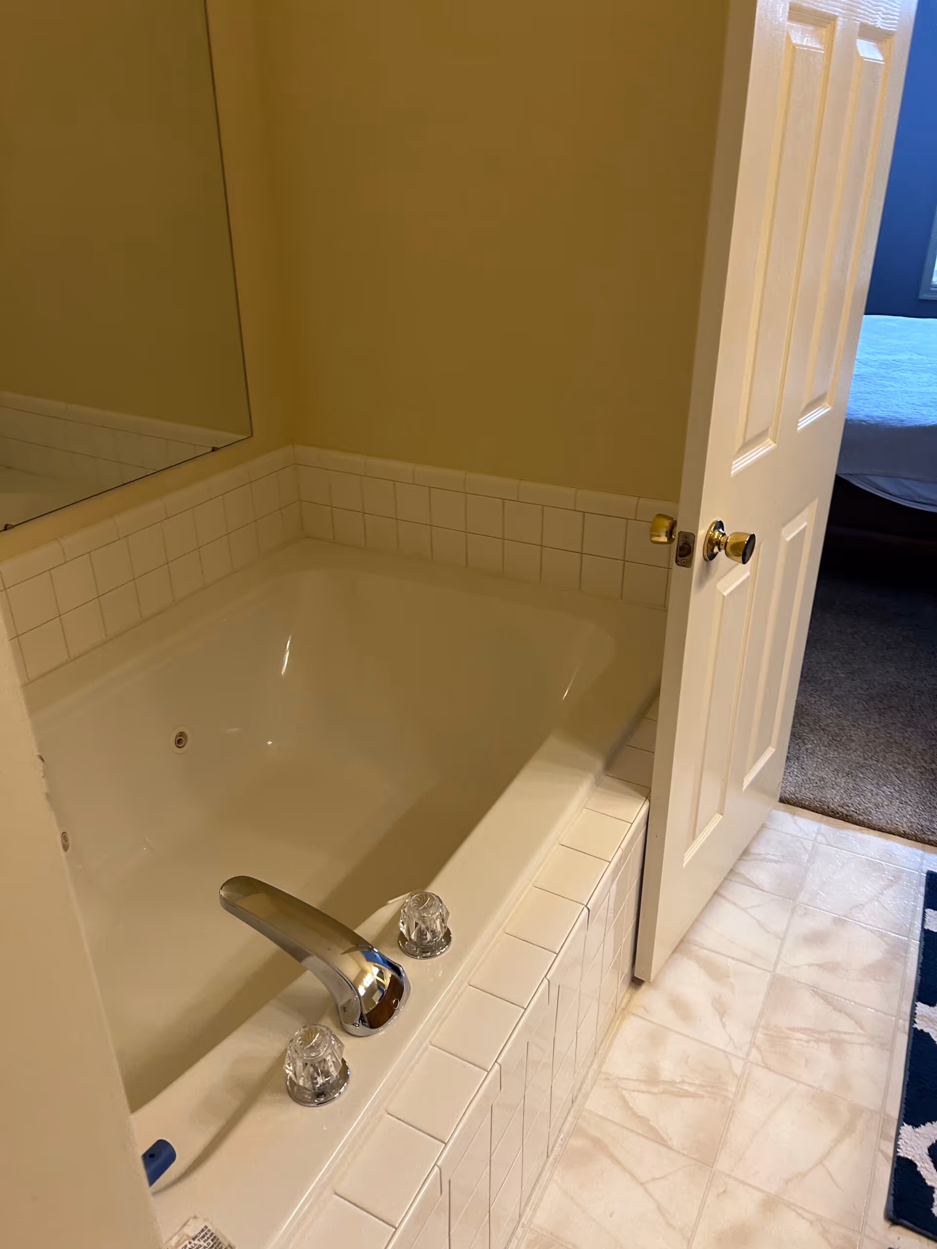 Brown primary bathroom featuring a jacuzzi tub and tiled flooring in Harrisburg, PA.