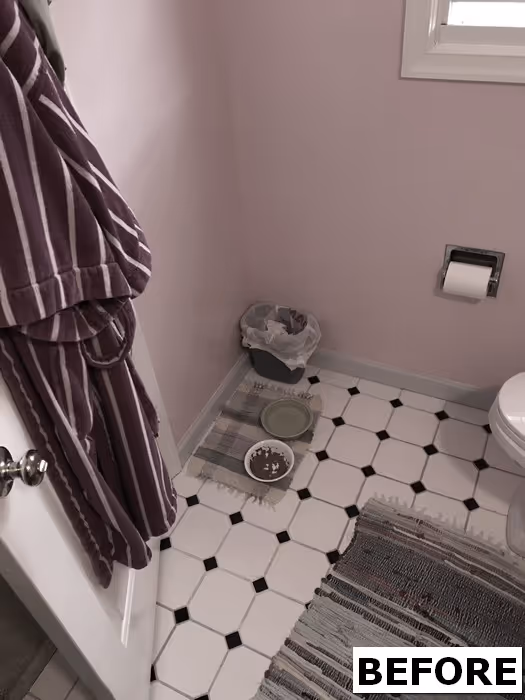Small bathroom with pink walls, black and white tiled floor, and a purple robe hanging. Mechanicsburg, PA
