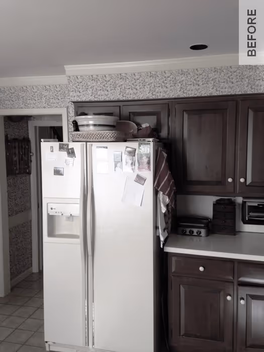 A traditional kitchen in Camp Hill, PA featuring dark wood cabinets, a side-by-side refrigerator, and patterned wallpaper.