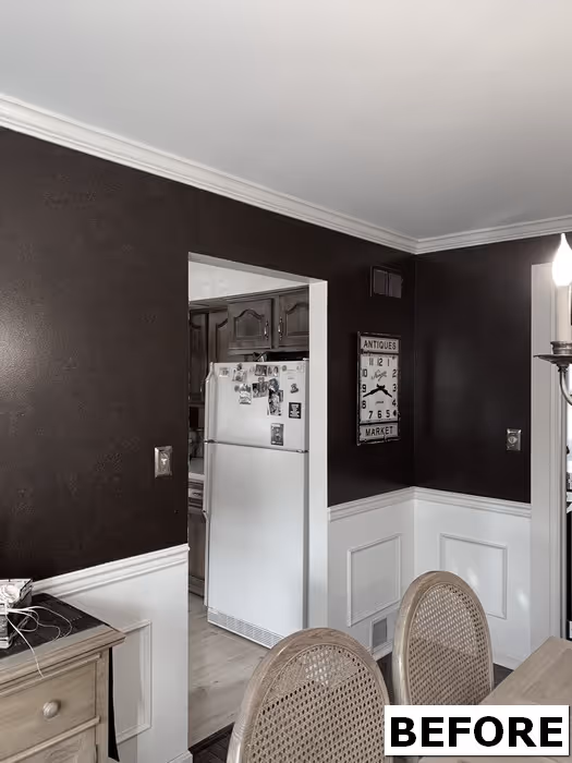 A dark brown dining room featuring a white wainscot, antique decor, and a view into the kitchen in Mechanicsburg, PA.