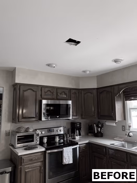 Before renovation image of a traditional kitchen in Mechanicsburg, PA featuring dark wood cabinets and ceiling fixture issues.