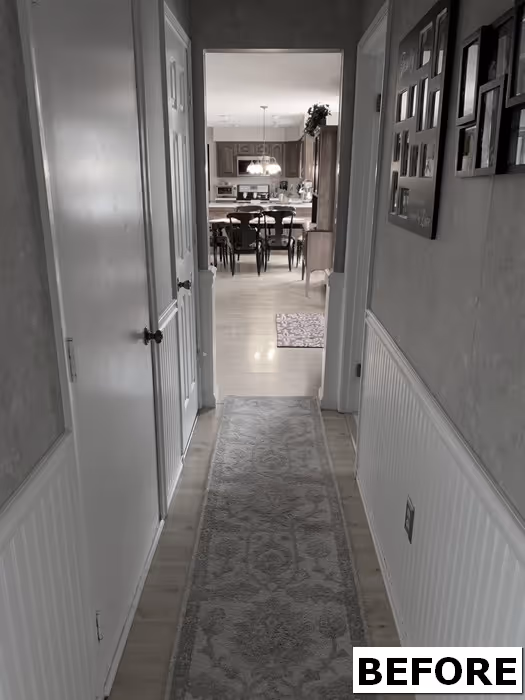 A hallway with wood flooring leading to a kitchen, featuring wainscoting and a rug, located in Mechanicsburg, PA.