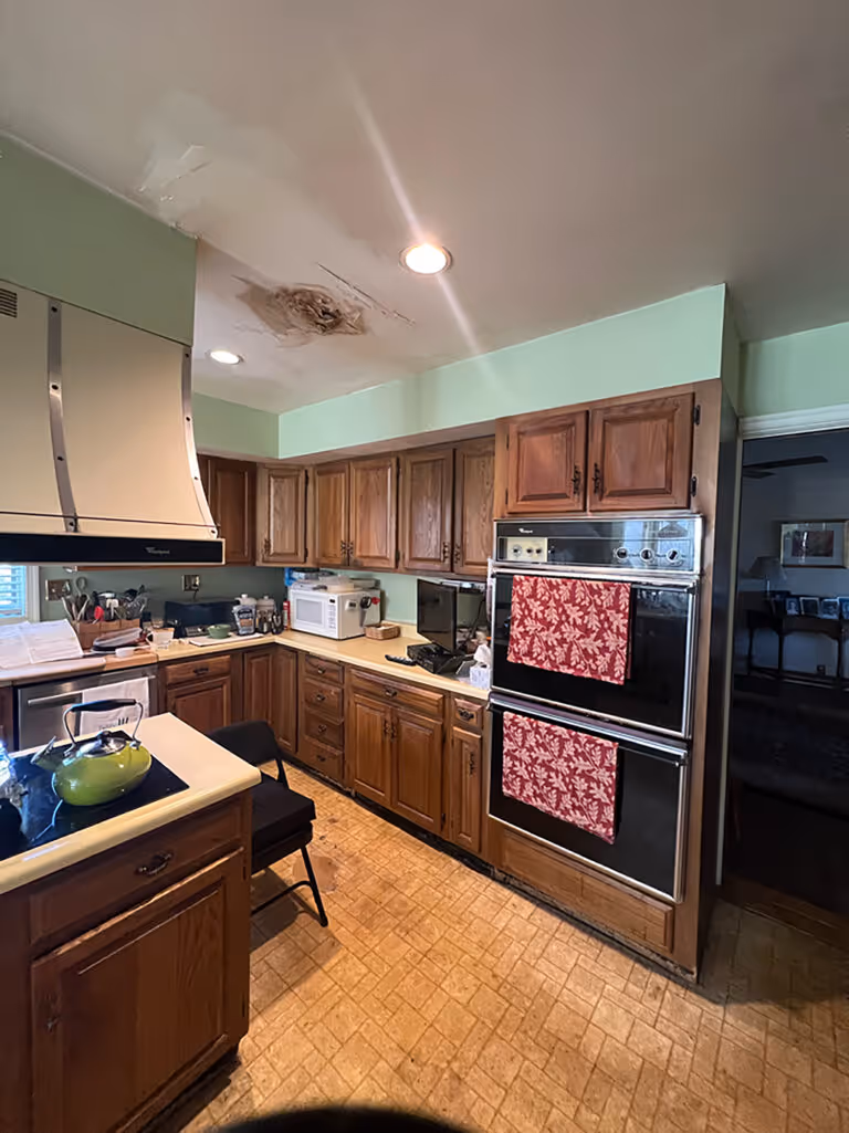 A traditional kitchen with wooden cabinets, beige countertops, and a green accent wall in Mechanicsburg, PA.