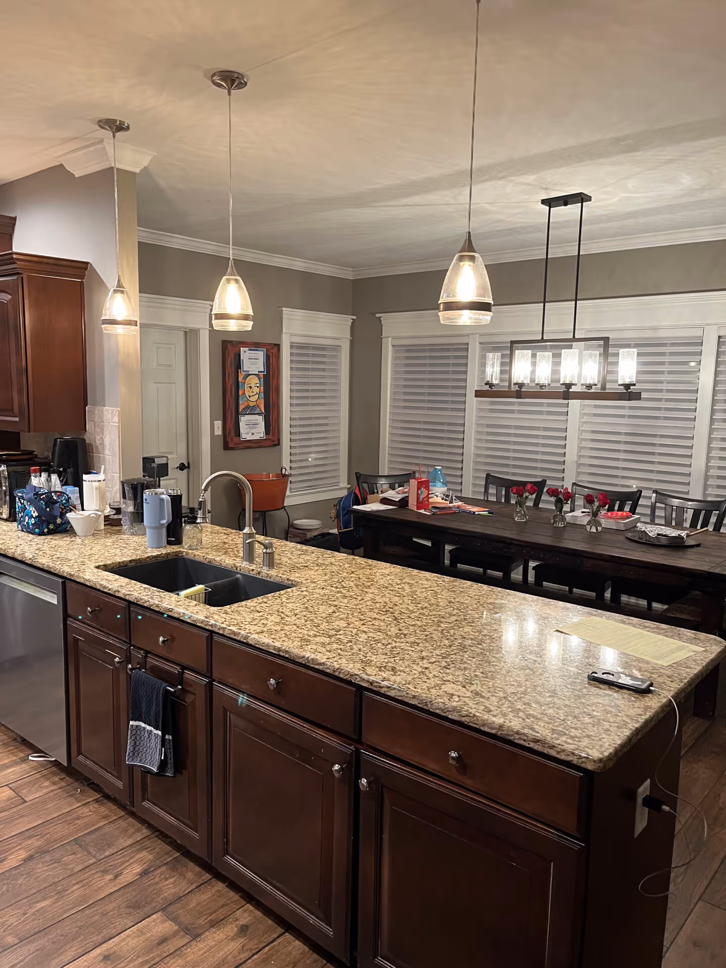 Modern kitchen with dark wood cabinets, granite countertop, and stylish pendant lighting, ideal for home renovation enthusiasts.