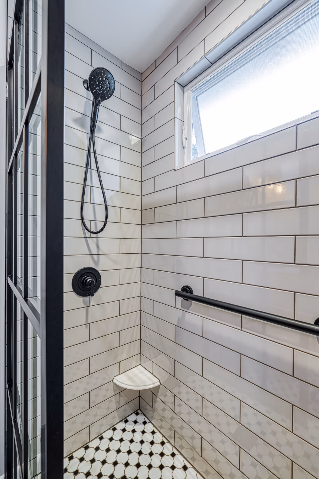 Stylish bathroom shower featuring subway tile, a sleek black showerhead, and hexagon tile floor in Harrisburg, PA.
