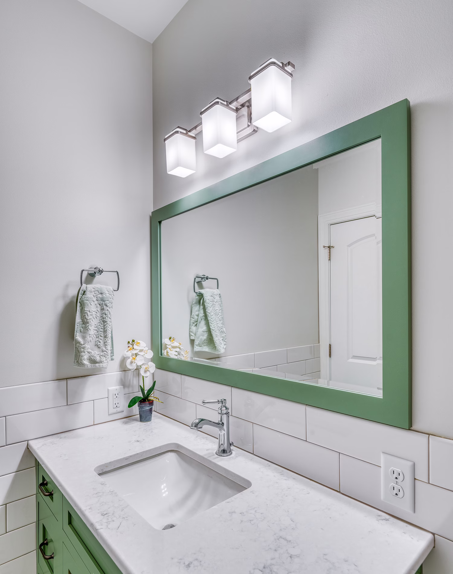 Modern bathroom sink featuring a green vanity, marble countertop, and stylish lighting in Mechanicsburg, PA.