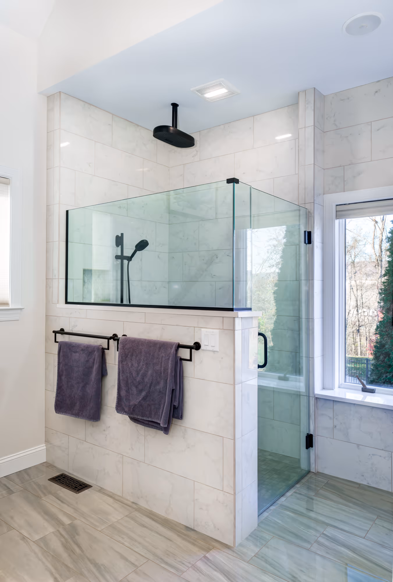 Modern bathroom in Mechanicsburg, PA featuring a luxurious glass shower, marble tiles, and stylish black fixtures for a sleek finish.