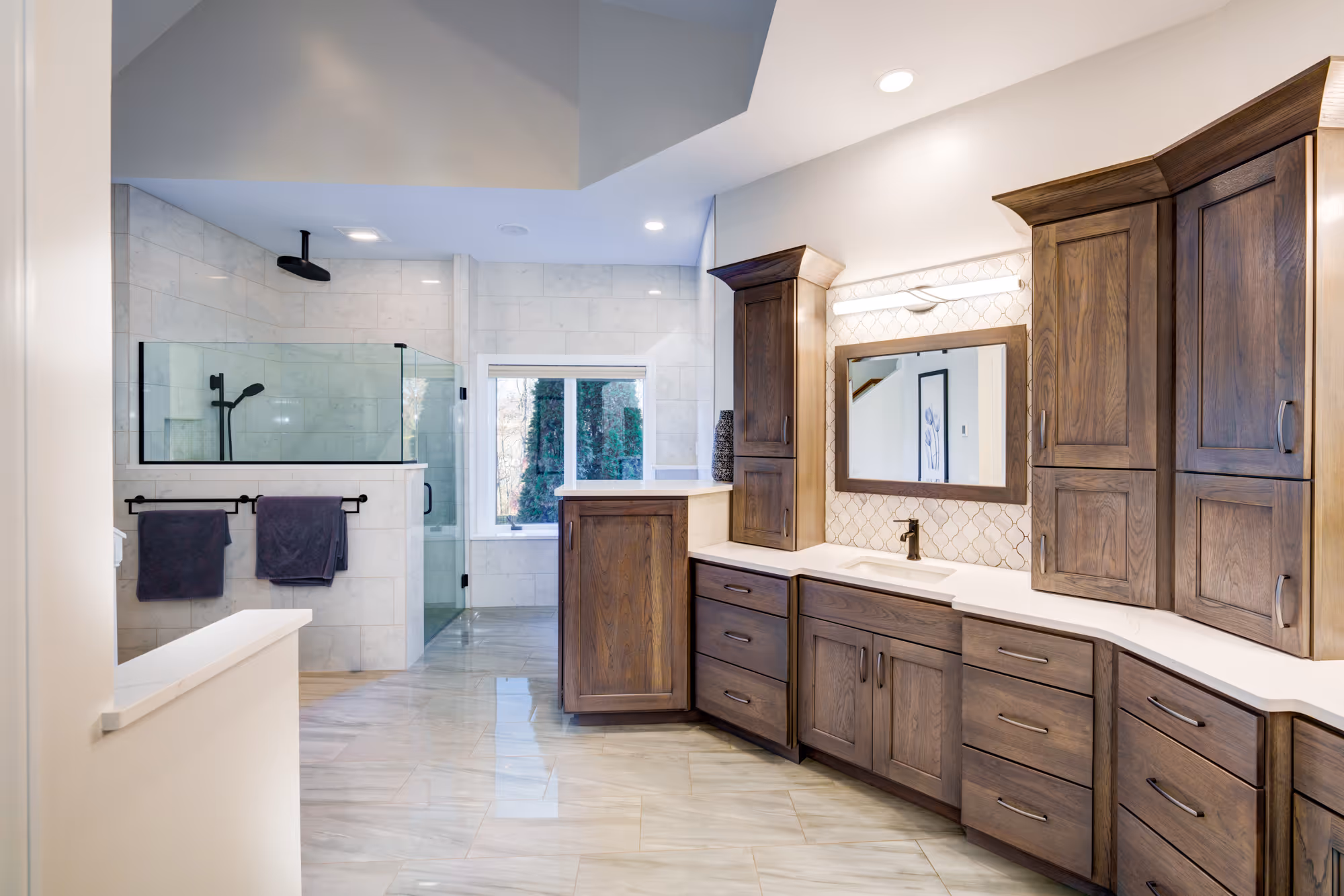Luxurious bathroom remodeled in Mechanicsburg, PA with wooden cabinets, marble floor tiles, and modern glass shower.