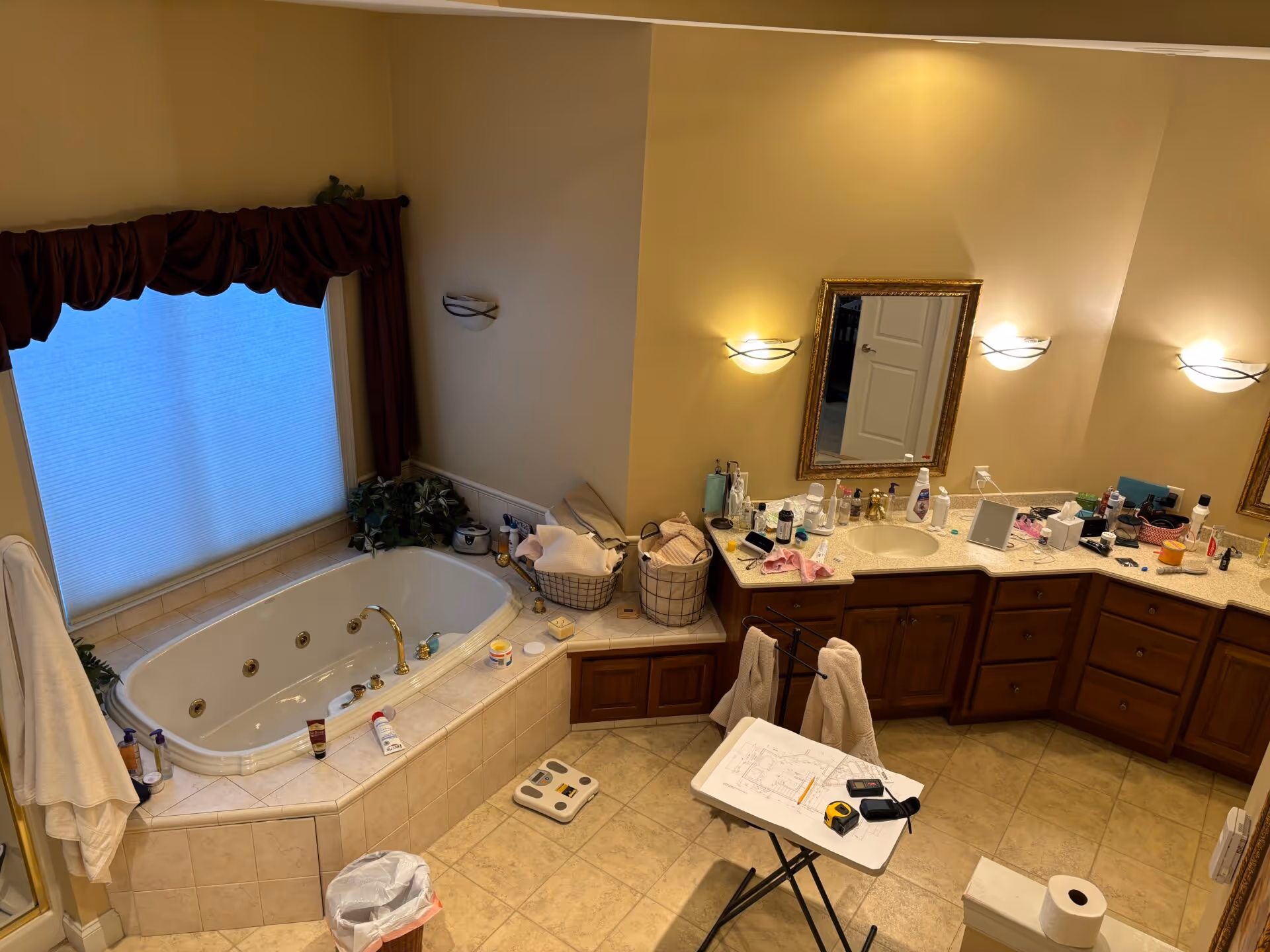 Primary bathroom in Mechanicsburg, PA featuring a jetted tub, wood cabinetry, and a cluttered countertop