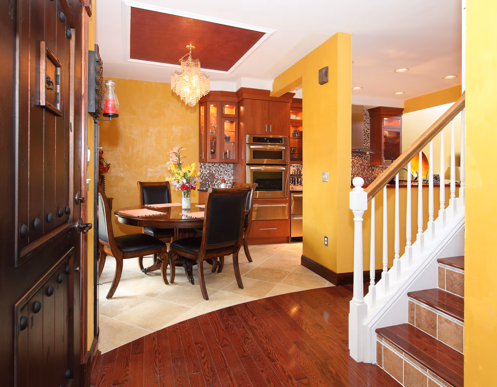 Inviting contemporary kitchen and dining area with warm yellow walls, modern appliances, and elegant chandelier in Harrisburg, PA
