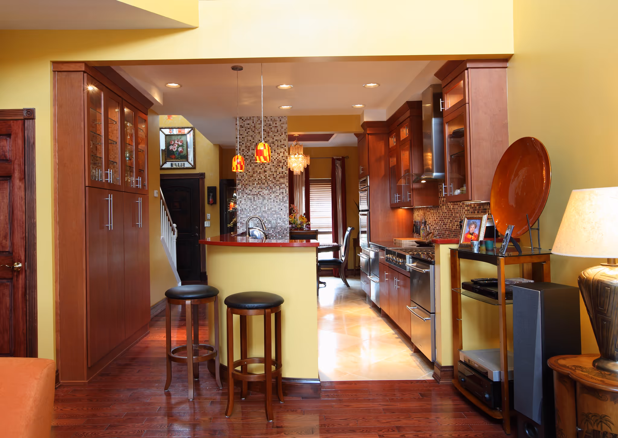 Modern kitchen with rich wood cabinetry, red accents, and mosaic tile backsplash in Harrisburg, PA.