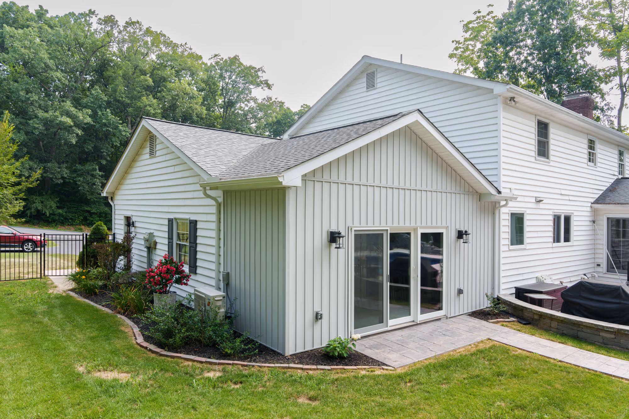 Modern home addition featuring large glass sliding doors, gray siding, and landscaped garden in gettysburg, pa.