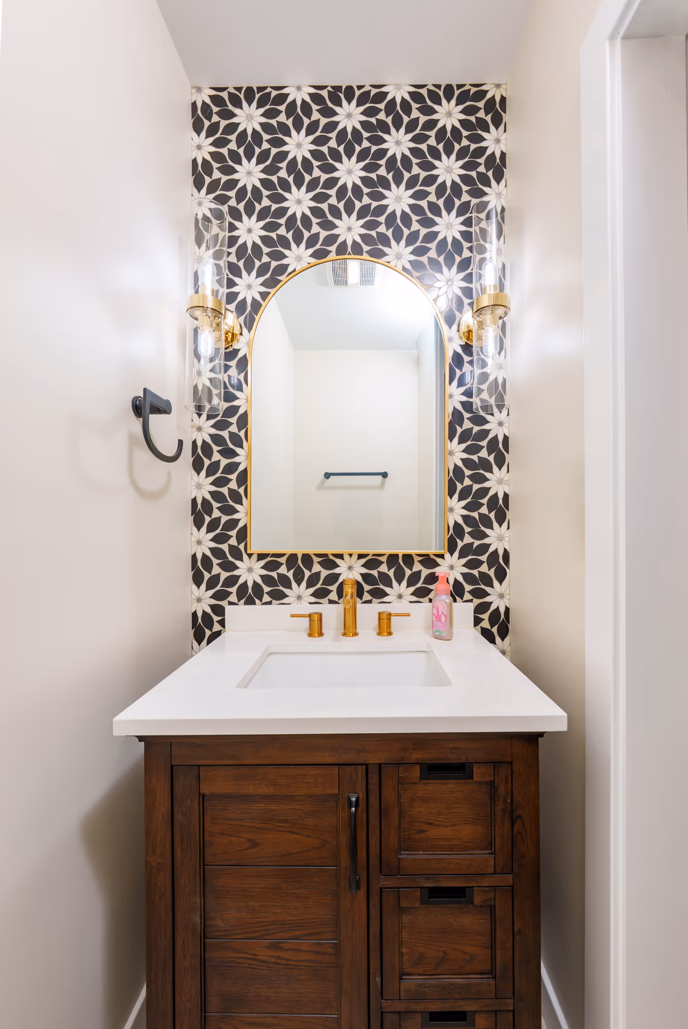 Modern bathroom in Gettysburg, PA featuring a stylish wood vanity, gold fixtures, and a patterned accent wall.